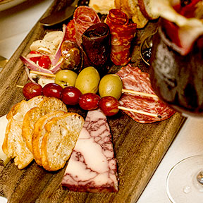 Charcuterie board with fruits and cheeses and a glass of wine